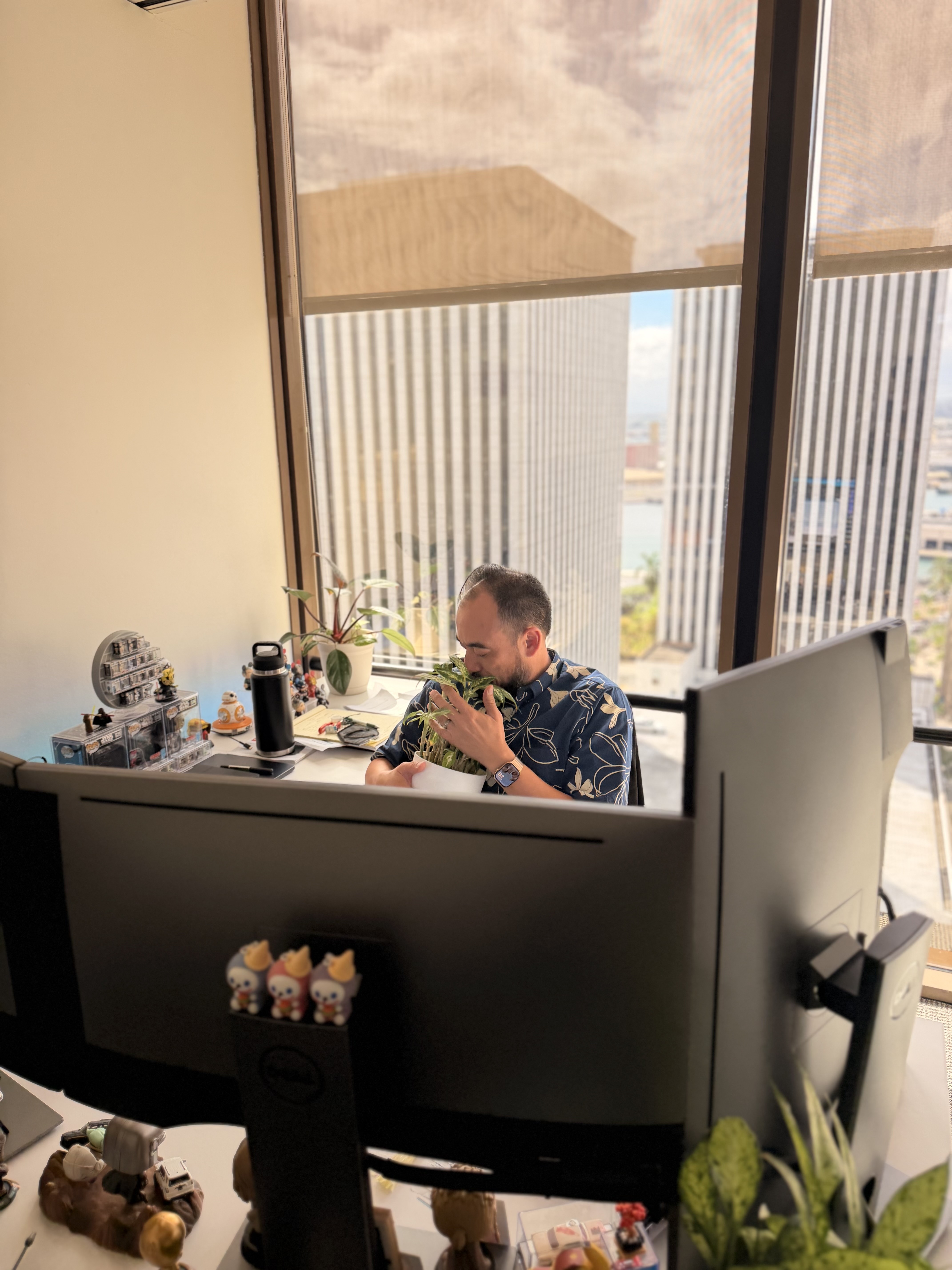 Eric Newhouse at his desk, smelling a plant